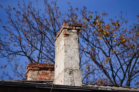 A chimney with a brick cap and a tree in the background. Foto stock