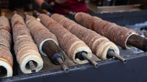 Chimney cake baking on rotating rolls street food dessert Stock Footage 331812169