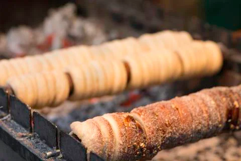 Chimney cake baking on a spit over charcoal fire Stock Photos