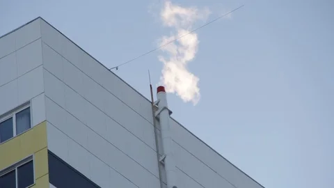 From the chimney comes white smoke backlit by the sun on the roof Stock Footage 125177026