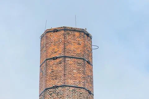 Chimney made of red bricks and a kestrel sitting on the top Stock Photos