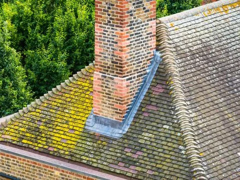 A chimney stack with new lead flashing, roof tiles and brick detail. Stock Photos