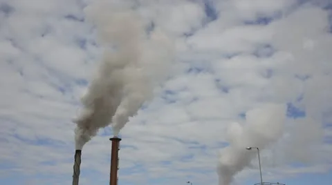 Chimneys emit smoke into a cloudy sky Stock Footage 11235900