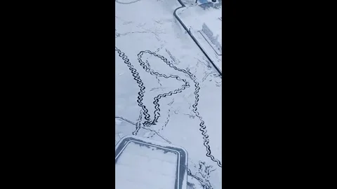 China: Chinese man joyfully creates patterns in snowy courtyard Stock Footage 327436737