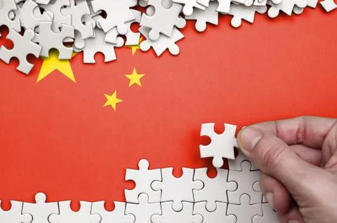 China flag  is depicted on a table on which the human hand folds a puzzle of  写真素材