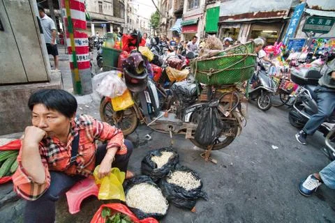 China wet market.Buying vegetables while riding electric bike Hainan China Stock Photos