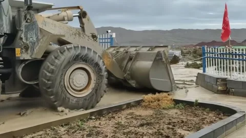 China: Wheel loader breaks concrete barrier to drain floodwater in Xinjia... Stock Footage 341421149