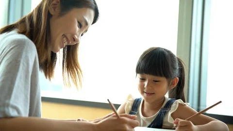 Chinese Asian single mum enjoying daughter drawing project Stock Footage