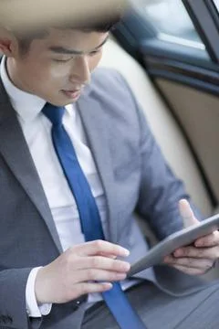  Chinese businessman using digital tablet in car back seat Beijing China C... Stock Photos