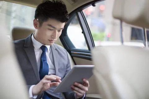  Chinese businessman using digital tablet in car back seat Beijing China C... Stock Photos