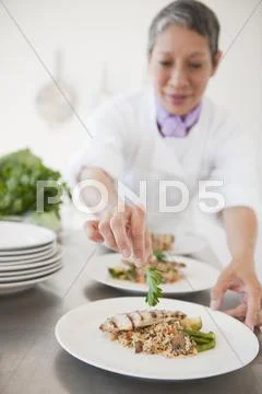 Chinese chef plating meals in professional kitchen Stock Photos