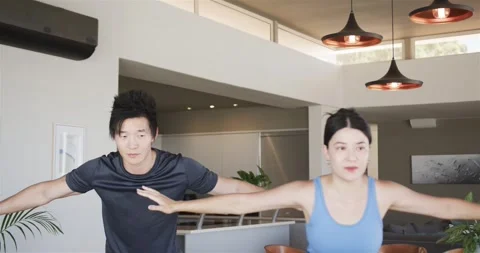 Chinese couple starting routine, raising, extending arms, folding in gymwear for Stock Footage 335987145