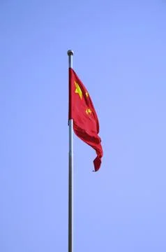 The Chinese Flag Flapping Against A Solid Blue Sky Stock Photos