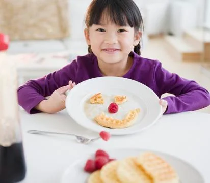 Chinese girl making a face on plate with waffle Stock Photos