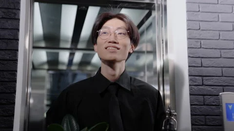 A Chinese man with a box of things comes out of the elevator. First working day Stock Footage 219460109