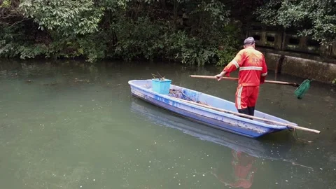 Chinese man cleaning pollution, plastic, trash in a lake, environmental problem Stock Footage 160788307