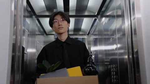 A Chinese man comes out of the elevator with a box. Last working day Stock Footage 201920500