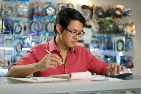 Chinese Man In Computer Shop Checking Bills And Invoices Stock Photos