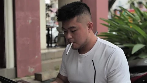 Chinese man smoking while working at the cafe in front of laptop and typing Video stock 172393129