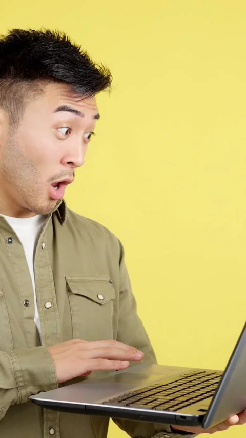 Chinese man with a surprised look using a laptop Stockbeeldmateriaal 244745244