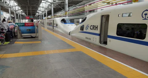 Chinese passengers queue to exit escalator, camera pan to bullet train Stock Footage 329461374