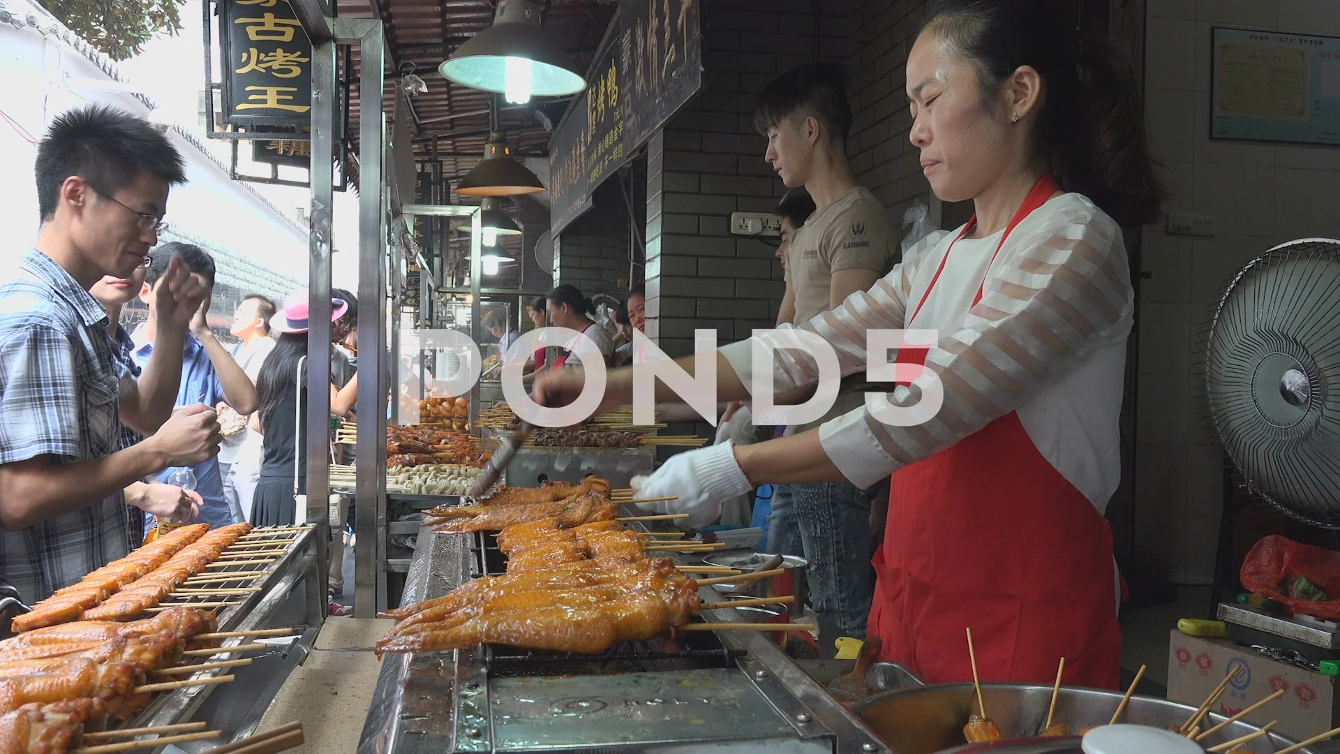 Chinese street vendor prepares fresh chicken kebabs at popular food market