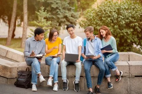 Chinese Student Showing Educational Website On Laptop To Coursemates Outside Stock Photos
