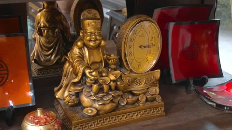 Chinese-style table clock features God of Wealth statue holding gold ingots Stock Footage 340562880