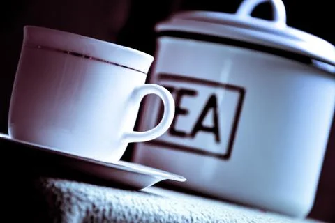 Chinese tea with tea leaf from tin and white cup and saucer on dark backdrop Stock Photos