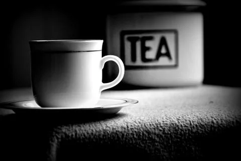 Chinese tea with tea leaf from tin and white cup and saucer on dark backdrop Stock Photos