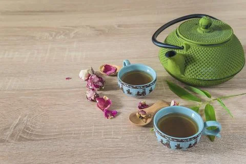 Chinese tea time concept: two chinese cups of tea, green teapot and petal o.. Stock Photos