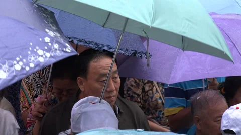 Chinese tourists use umbrellas while waiting in a queue in Fenghuang Stock Footage 60396270