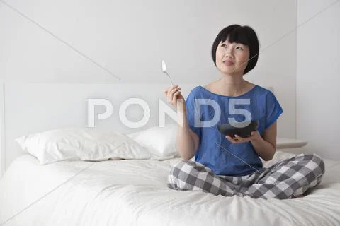 Chinese woman eating on bed Stock Photos