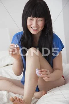 Chinese woman painting toenails on bed Stock Photos