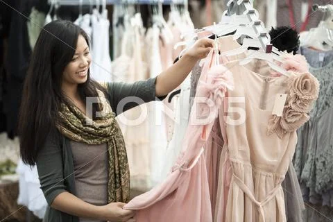 Chinese Woman Shopping For Dresses At Flea Market