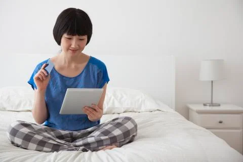 Chinese woman using tablet computer on bed Stock Photos