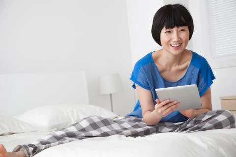 Chinese woman using tablet computer on bed 스톡 사진