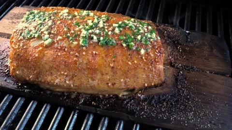 Chinook (Spring) salmon grilling on a cedar plank, basted with garlic butter. 库存影片 66322948