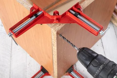 Chipboard in an angular carpentry clamp. Drilling in a furniture board. 스톡 사진