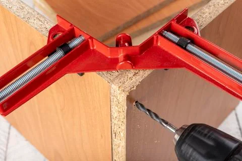 Chipboard in an angular carpentry clamp. Drilling in a furniture board. Stock Photos