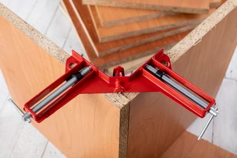 Chipboard in an angular carpentry clamp. Fixing the material for machining. Stock Photos