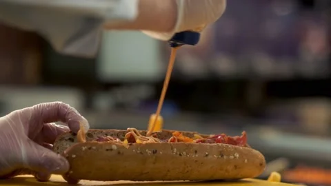 Chipotle sauce being poured over a sandwich bread roll in a deli slow Stock Footage 232753566