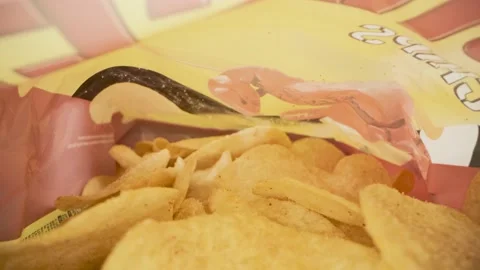 Chips in a bag for a quick snack on a dark background close up Stock Footage 153882594