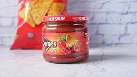 Chips packet and doritos salsa on table , Stock Footage 158884426