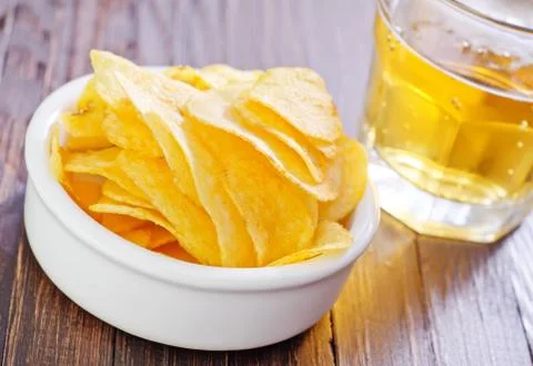 Chips from potato with beer on a table Stock Photos