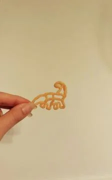 Chips in the shape of a dinosaur on a light background. Stock Photos