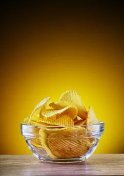 Chips in transparent plate on yellow background Stock Photos