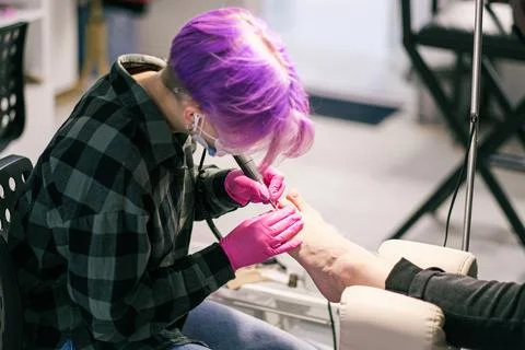 Chiropody master processes nails of female client in the beauty salon Stock Photos