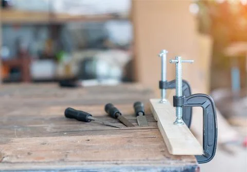 Chisel and Screw Clamp pin on wood table. Stock Photos