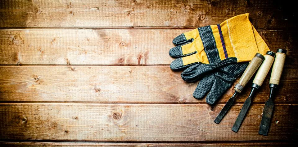 Chisel with construction gloves on the table. Stock Photos